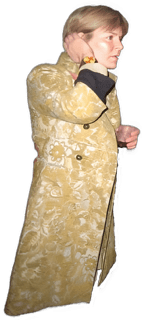 An enhanced full body photographic cutout of a young adult Amy M. Schmitter turned to her left wearing a full length golden yellow velvet floral patterned tapestry long coat with white floral embroidery patterns used to visually identify her.