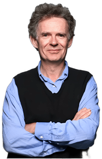 A reversed enhanced color photographic headshot and torso cutout of a glasses free Galen Strawson wearing a medium blue shirt under a dark blue sweater vest with his arms crossed used for visually identifying him.