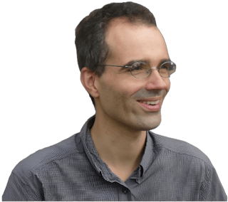 A reversed enhanced color photographic headshot and torso cutout of a smiling glasses adorned Lionel Shapiro wearing a gray collared shirt with his head turned away from viewer towards his left used for visually identifying him.