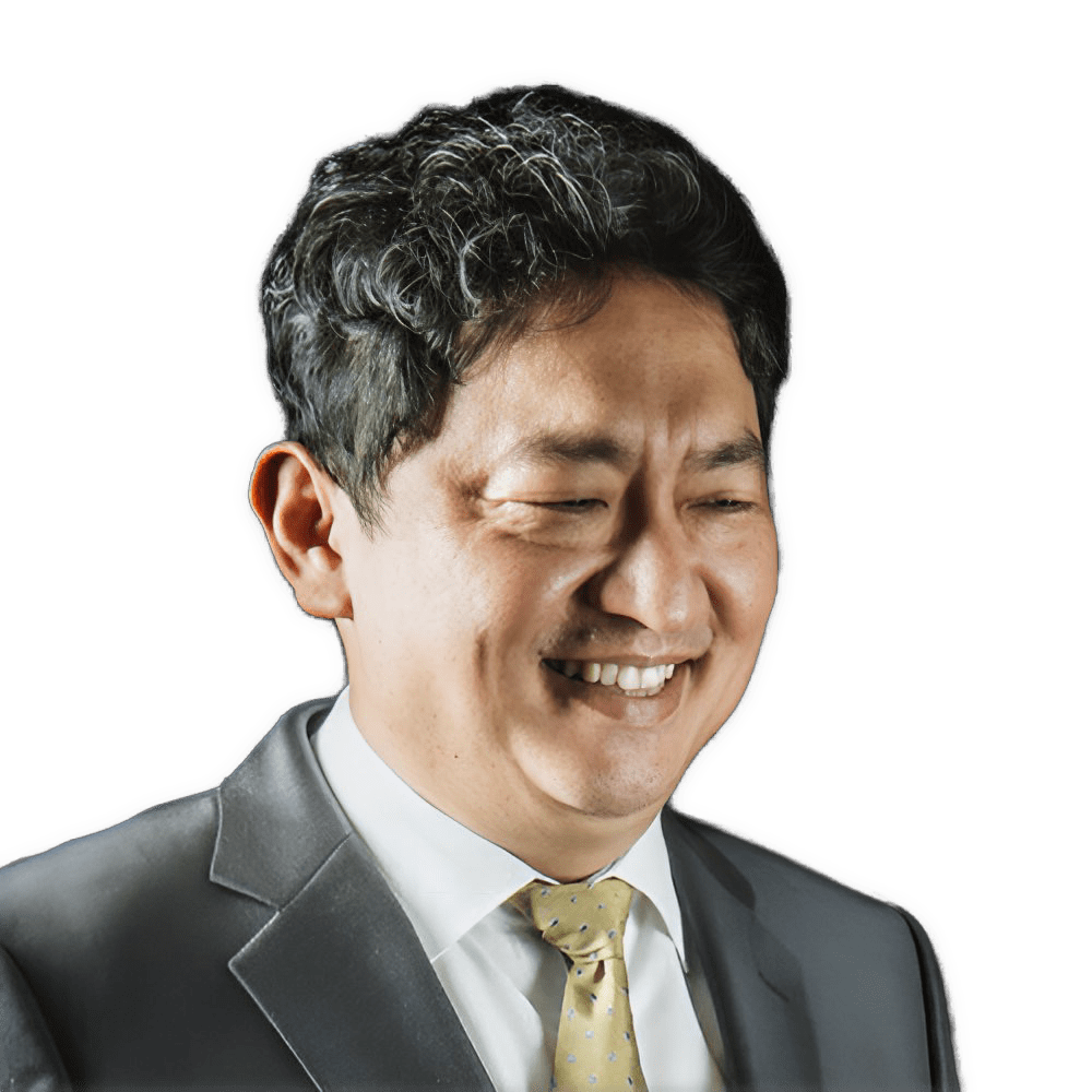 An enhanced color photographic headshot cutout of a smiling Sukjae Lee wearing a gray suit jacket, white collared shirt, and a  golden colored tie used to visually identify him.