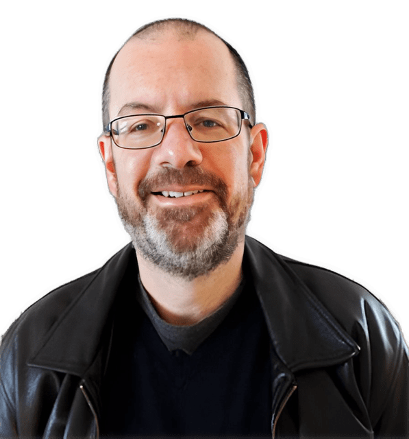 A color photographic shoulders and headshot of a glasses wearing and smiling Byron Williston with a salt and pepper colored beard and mustache and wearing a black shirt under a shiny black jacket used to visually identify him.