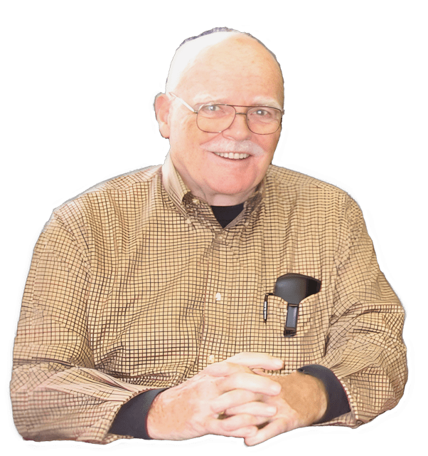 An enhanced upper torso and headshot photographic cutout of a smiling with glasses on Norman J. Wells wearing a black long sleeved shirt under a tan-yellow cross-hatched shirt with a black glasses case in his left  shirt front pocket and with his fingers interlaced resting on a table (unseen) used to visually identify him.
