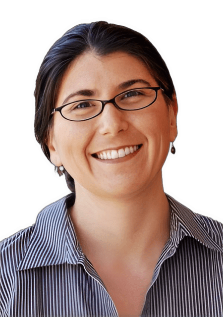 A reversed enhanced color photographic headshot cutout of a smiling and oval glasses wearing Dr. R. Brassfield with drop earrings and wearing a dark blue shirt with very thin white stripes used to visually identify her.