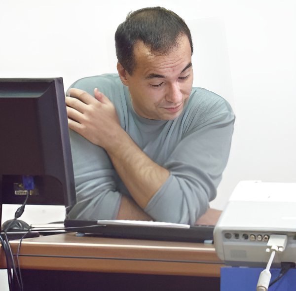 An enhanced photographic upper torso and headshot cutout of a clean shaven Predrag Milidrag sitting at a table with a computer monitor – keyboard looking down while wearing a gray long sleeved shirt used to visually identify him.