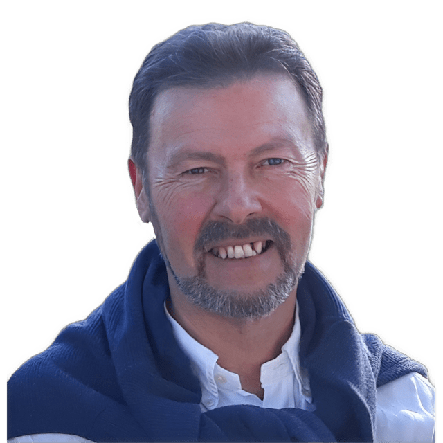 An enhanced color photographic headshot cutout of Alan R. Malachowski, showing his teeth and wearing a blue sweatshirt tied loosely around his neck with a white shirt that has  a buttoned down collar, is used for visual identification.
