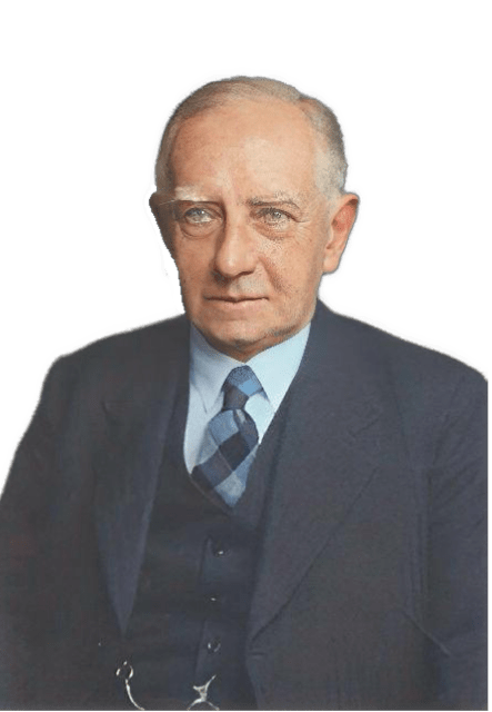An enhanced colorized photographic upper torso and headshot cutout of Norman Kemp Smith wearing a dark gray three-piece suit with a tartan blue tie and a gold watch chain in his vest is used for visual identification.