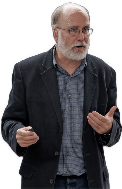 An enhanced colorized photographic upper torso and headshot cutout of a white-bearded, glasses-wearing Gary Hatfield looking to his left with both hands held up, palms up, gesticulating, are used for visual identification. He wears a dark gray suit jacket over a medium gray patterned shirt unbuttoned at the neck.