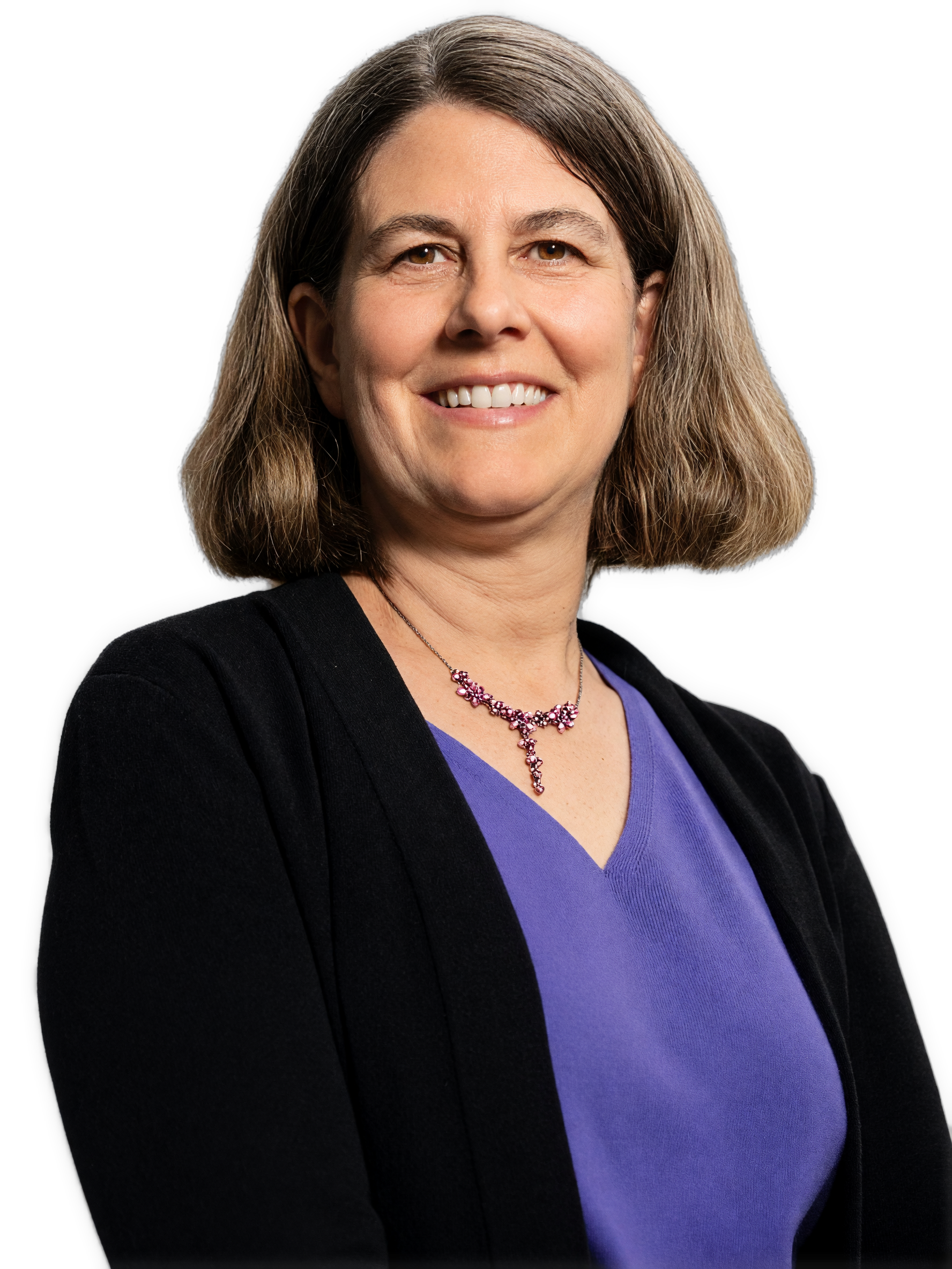 A reversed cutout of a smiling Karen Detlefsen in 2021 with shoulder-length brown hair wears a purple top, a black cardigan, and a pink beaded necklace.